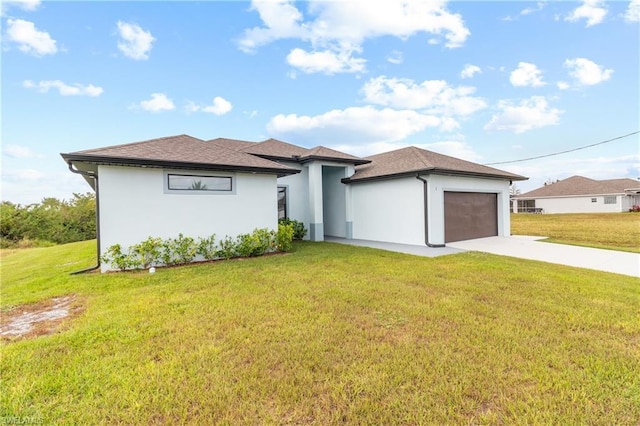 prairie-style house with an attached garage, concrete driveway, a front yard, and stucco siding