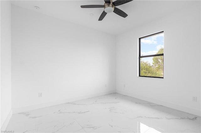 spare room with ceiling fan, marble finish floor, and baseboards