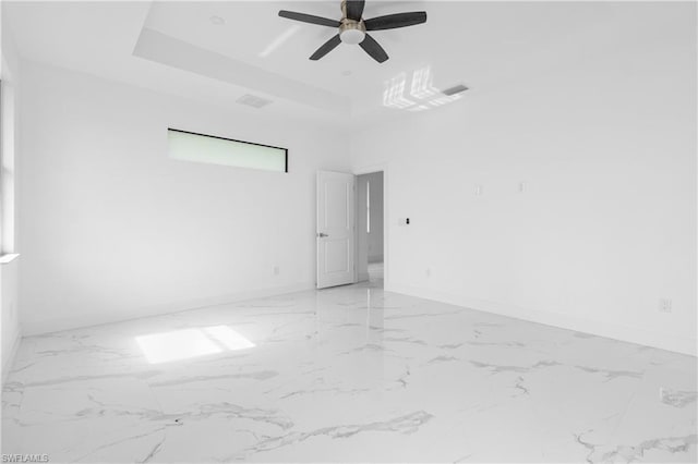 spare room featuring a raised ceiling, visible vents, and baseboards