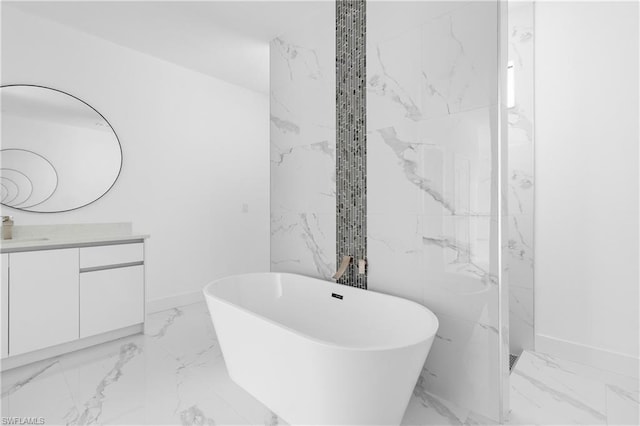 full bathroom with marble finish floor, a soaking tub, vanity, and baseboards