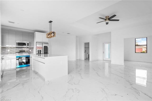 kitchen with decorative light fixtures, stainless steel appliances, light countertops, a kitchen island, and modern cabinets