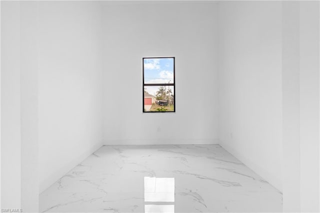 unfurnished room featuring marble finish floor and baseboards