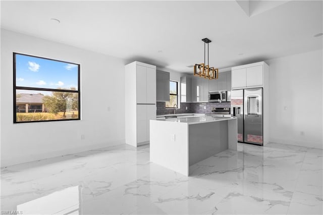 kitchen featuring stainless steel appliances, light countertops, a center island, modern cabinets, and pendant lighting