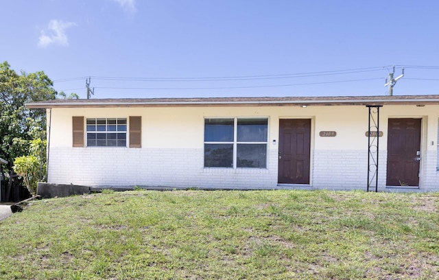 ranch-style house with a front yard and brick siding