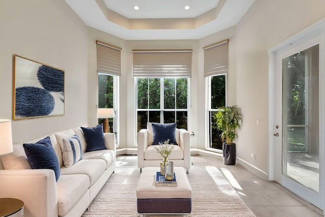 living area featuring light tile patterned floors, recessed lighting, a raised ceiling, a towering ceiling, and baseboards