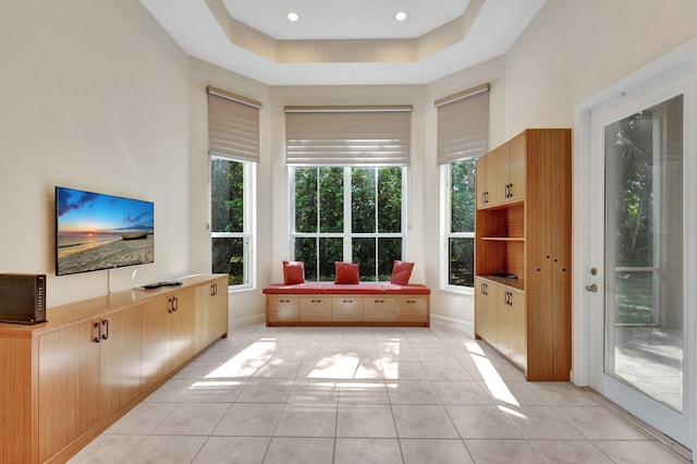 interior space with light tile patterned floors, recessed lighting, a high ceiling, baseboards, and a raised ceiling