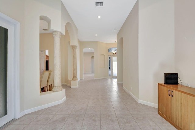 corridor with arched walkways, decorative columns, light tile patterned floors, visible vents, and baseboards