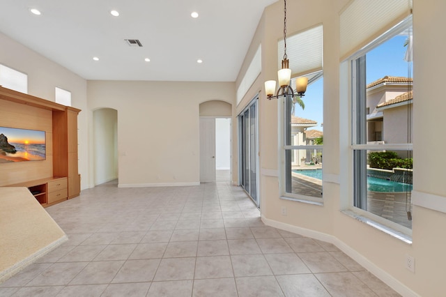 interior space featuring light tile patterned floors, visible vents, arched walkways, an inviting chandelier, and recessed lighting