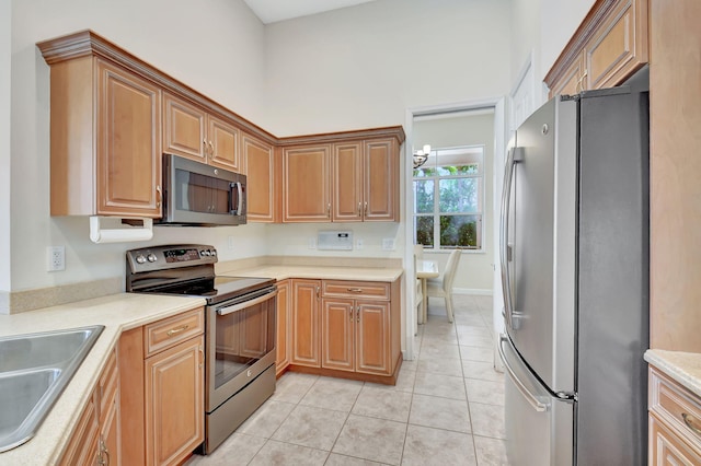 kitchen featuring sink, light tile patterned floors, stainless steel appliances, and a high ceiling