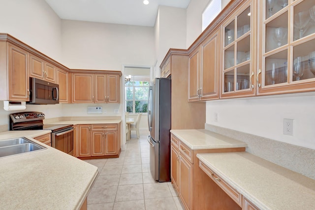 kitchen with glass insert cabinets, appliances with stainless steel finishes, and light countertops