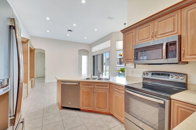 kitchen with light tile patterned floors, arched walkways, appliances with stainless steel finishes, light countertops, and a sink