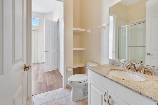 bathroom with tile patterned floors, toilet, a shower with shower door, and vanity