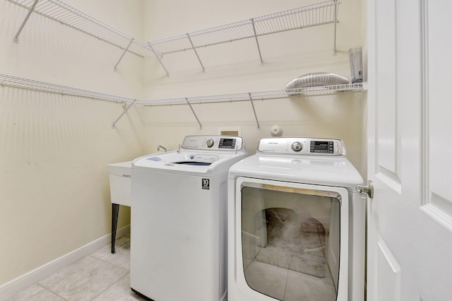 washroom with baseboards, laundry area, light tile patterned floors, and washer and dryer