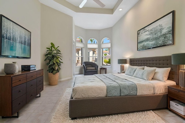 bedroom with ceiling fan, a high ceiling, light tile patterned flooring, and baseboards