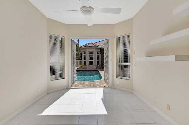 doorway featuring light tile patterned flooring and ceiling fan