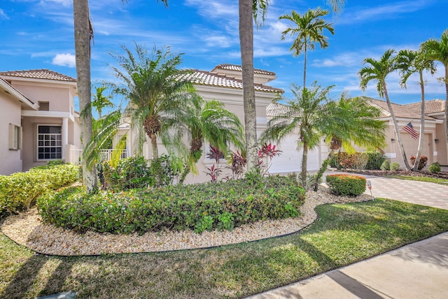 exterior space with a garage, decorative driveway, a tile roof, and stucco siding