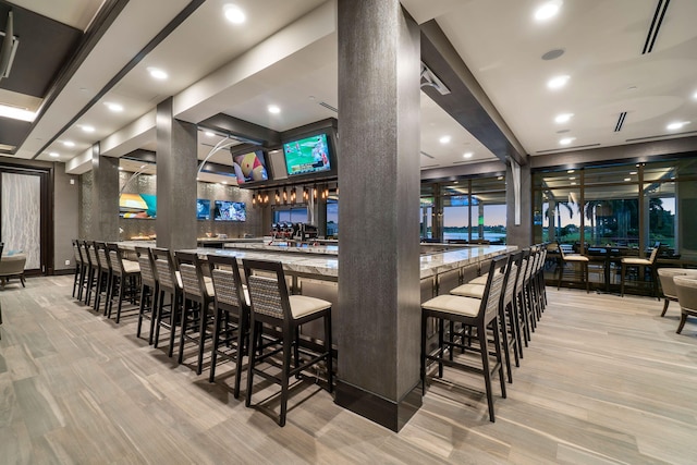 bar featuring a community bar, recessed lighting, and light wood-style flooring