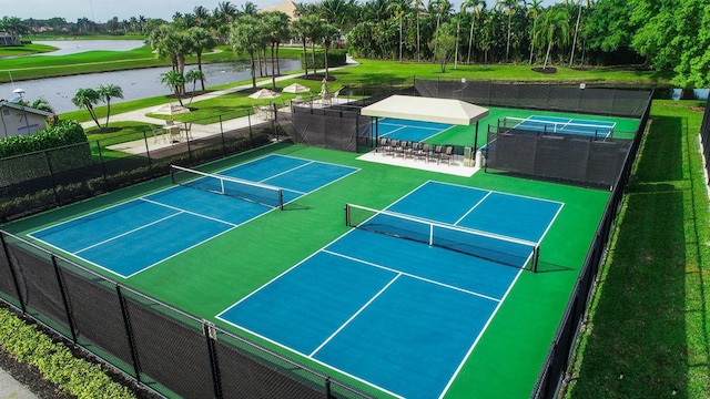 view of sport court featuring a water view and fence