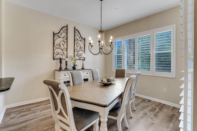 dining room featuring light wood finished floors, baseboards, and a chandelier