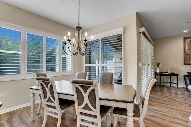 dining area with a chandelier, baseboards, and light wood finished floors