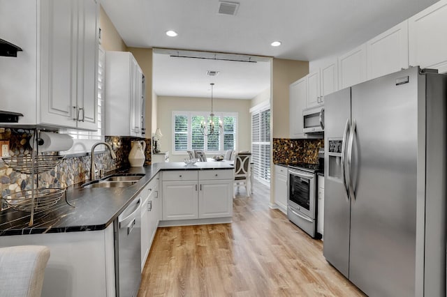 kitchen featuring tasteful backsplash, visible vents, dark countertops, stainless steel appliances, and a sink