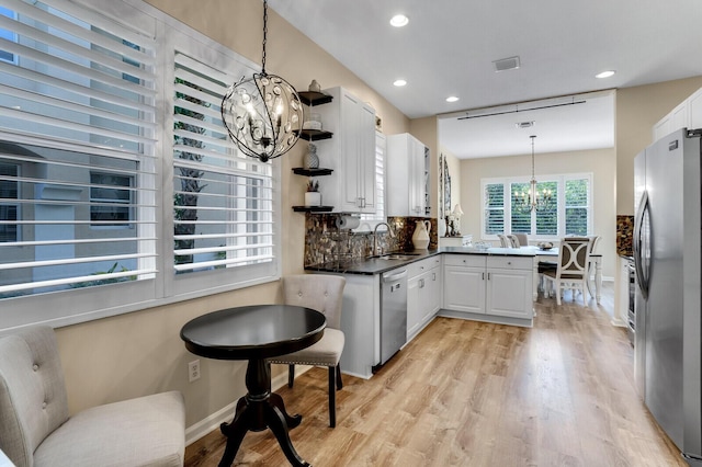 kitchen featuring a notable chandelier, stainless steel appliances, a peninsula, a sink, and open shelves