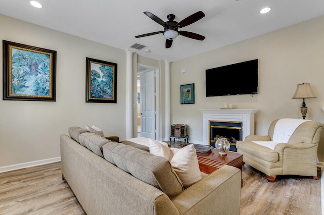 living area featuring visible vents, baseboards, light wood-style flooring, a fireplace, and recessed lighting