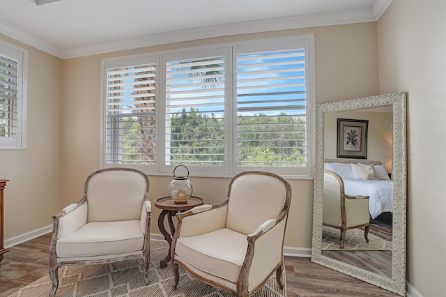 sitting room featuring baseboards, wood finished floors, and crown molding