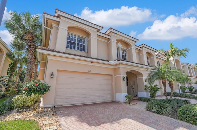 view of front of property featuring a garage, decorative driveway, and stucco siding