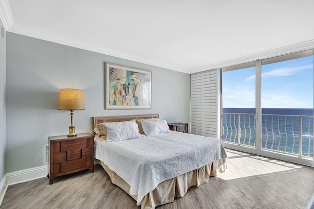 bedroom with a water view, floor to ceiling windows, crown molding, and light wood-type flooring