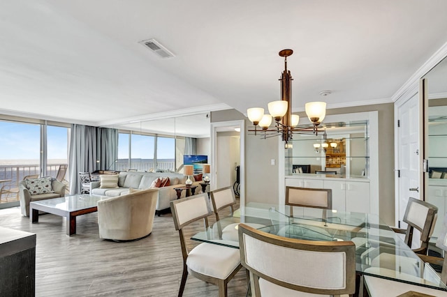 dining area featuring crown molding, a chandelier, and hardwood / wood-style flooring