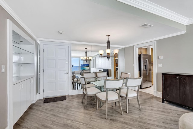 dining space featuring an inviting chandelier, crown molding, and light hardwood / wood-style floors