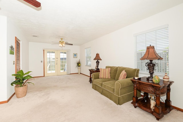 living room featuring ceiling fan, french doors, baseboards, and light carpet