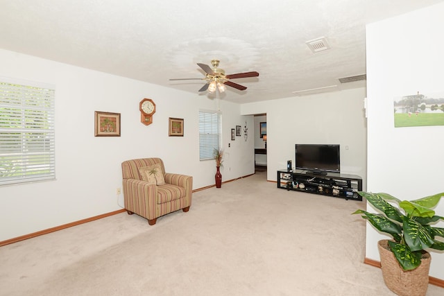 living room featuring light carpet, baseboards, and a ceiling fan