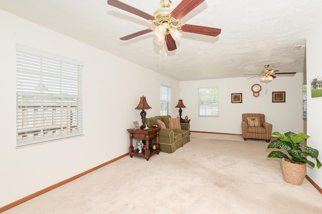 living area featuring ceiling fan, carpet floors, and baseboards