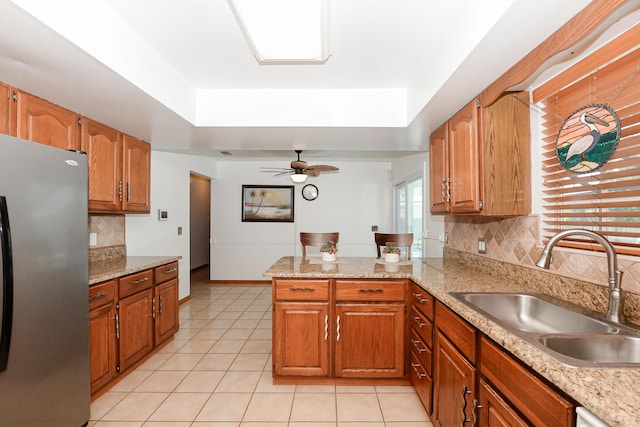kitchen with freestanding refrigerator, a sink, a raised ceiling, and light countertops