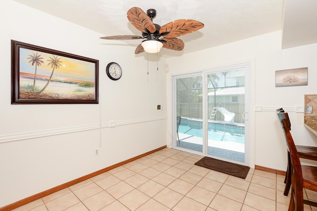 unfurnished dining area with ceiling fan, baseboards, and light tile patterned floors