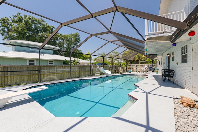 view of swimming pool with a water slide, a patio, a fenced backyard, a lanai, and a diving board