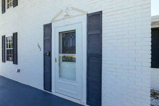view of exterior entry featuring brick siding