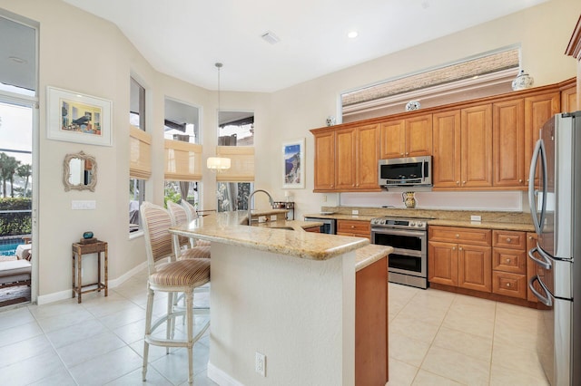 kitchen featuring sink, a breakfast bar, stainless steel appliances, light stone counters, and kitchen peninsula