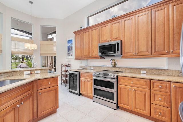 kitchen featuring light stone counters, a notable chandelier, stainless steel appliances, brown cabinetry, and beverage cooler