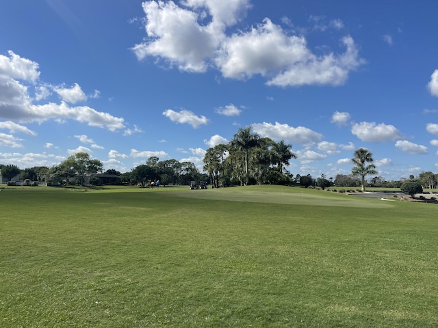 view of property's community with view of golf course and a yard