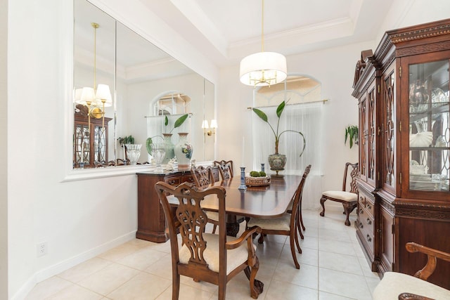 dining space with light tile patterned floors, baseboards, a tray ceiling, and crown molding