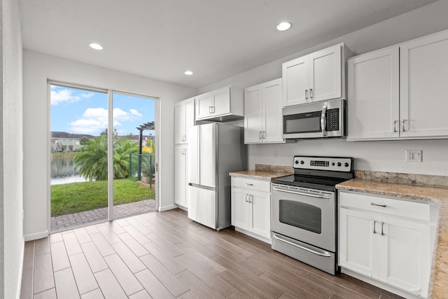 kitchen with appliances with stainless steel finishes, wood finish floors, recessed lighting, and white cabinets