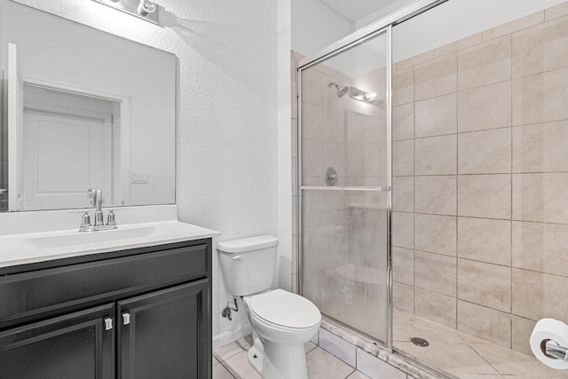 bathroom featuring toilet, a stall shower, tile patterned flooring, and vanity