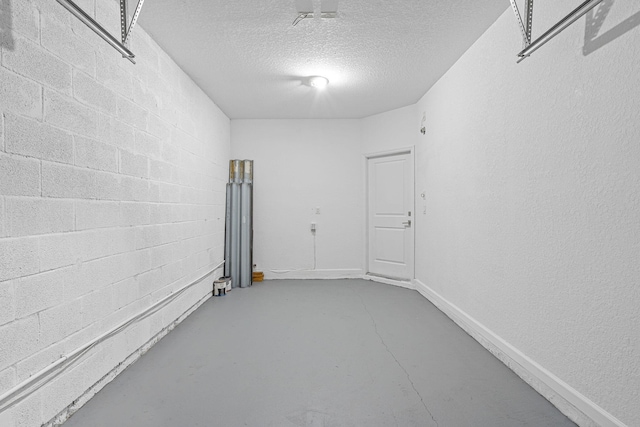 spare room featuring a textured ceiling, concrete block wall, and finished concrete floors