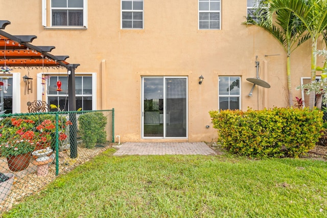 rear view of property featuring a yard, fence, a pergola, and stucco siding