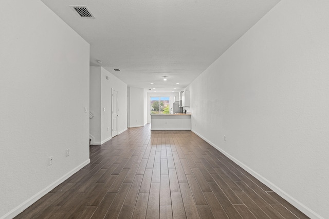 unfurnished room featuring dark wood-type flooring, visible vents, and baseboards