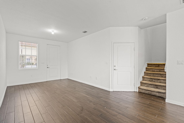 unfurnished room featuring dark wood-style floors, visible vents, baseboards, and stairs