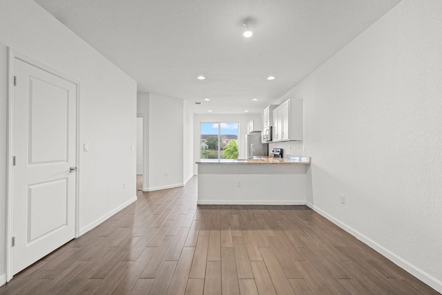 unfurnished living room with dark wood-type flooring, recessed lighting, and baseboards